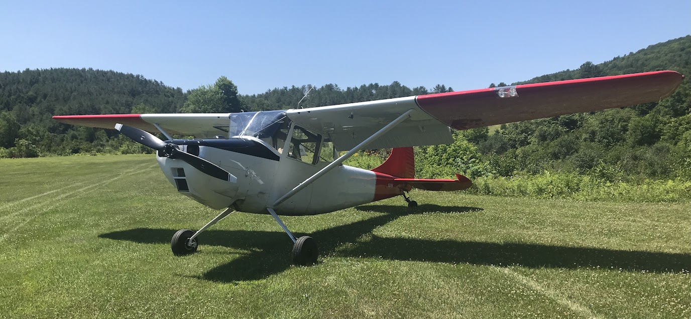 N24W Aeronca Champ on the grass runway at Post Mills Airport with Vermont hills in the background